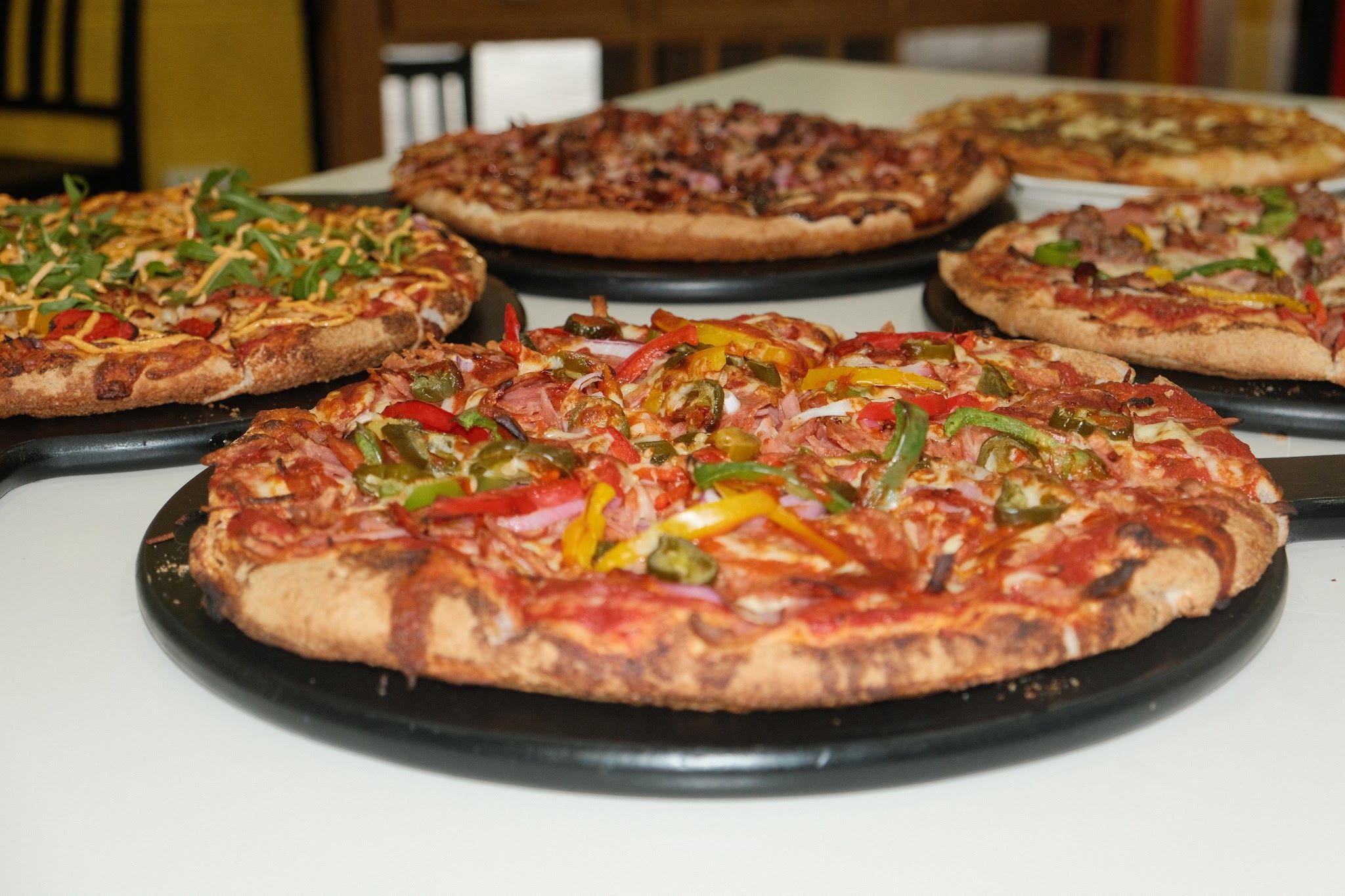 Five King Castello pizzas on black trays spread across a table