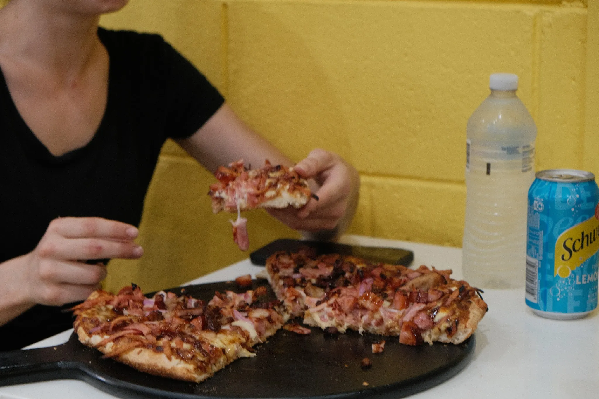 Woman eating pizza at King Castello with yellow brick wall behind